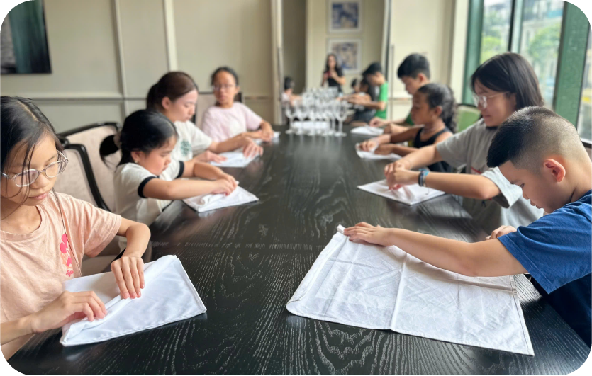 Các học viên thực hành gấp khăn tại bàn ăn
